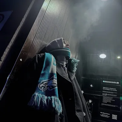 Night photograph of a friend in a beanie and Philadelphia Eagles scarf, breath fogging in the cold