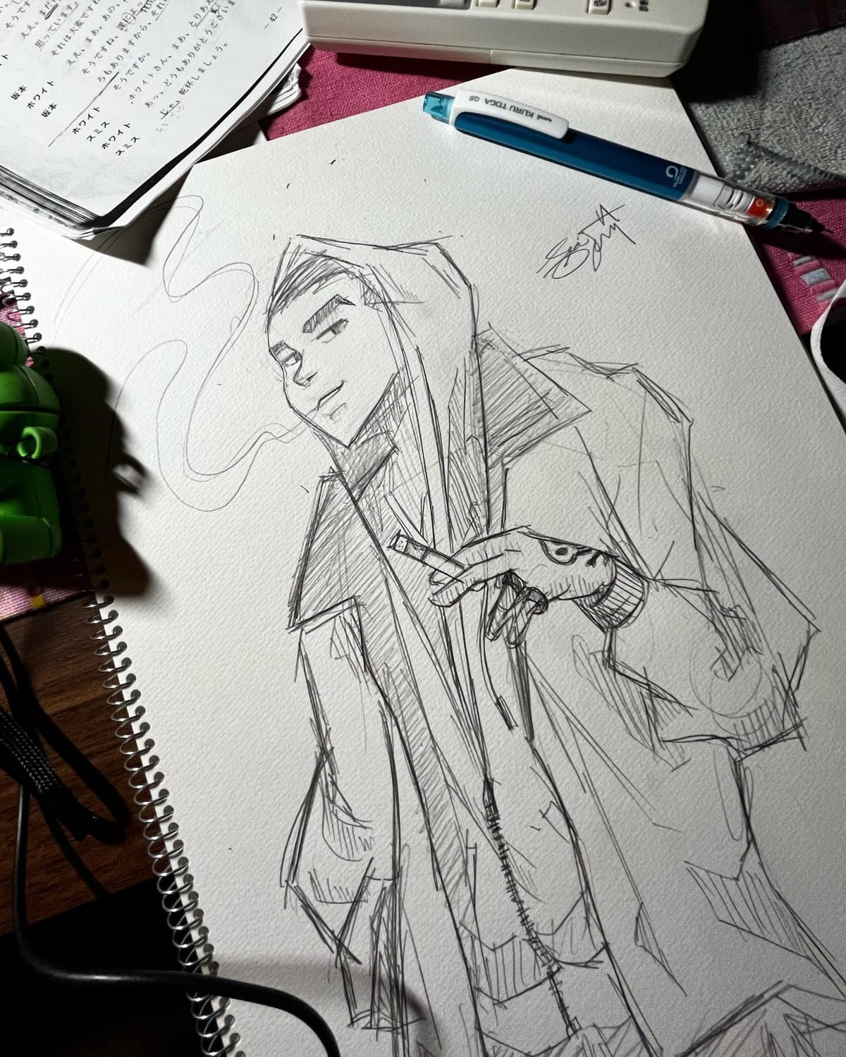 Mechanical-pencil sketch of a hooded figure in a long cloak, drawn on a sketchpad at a desk