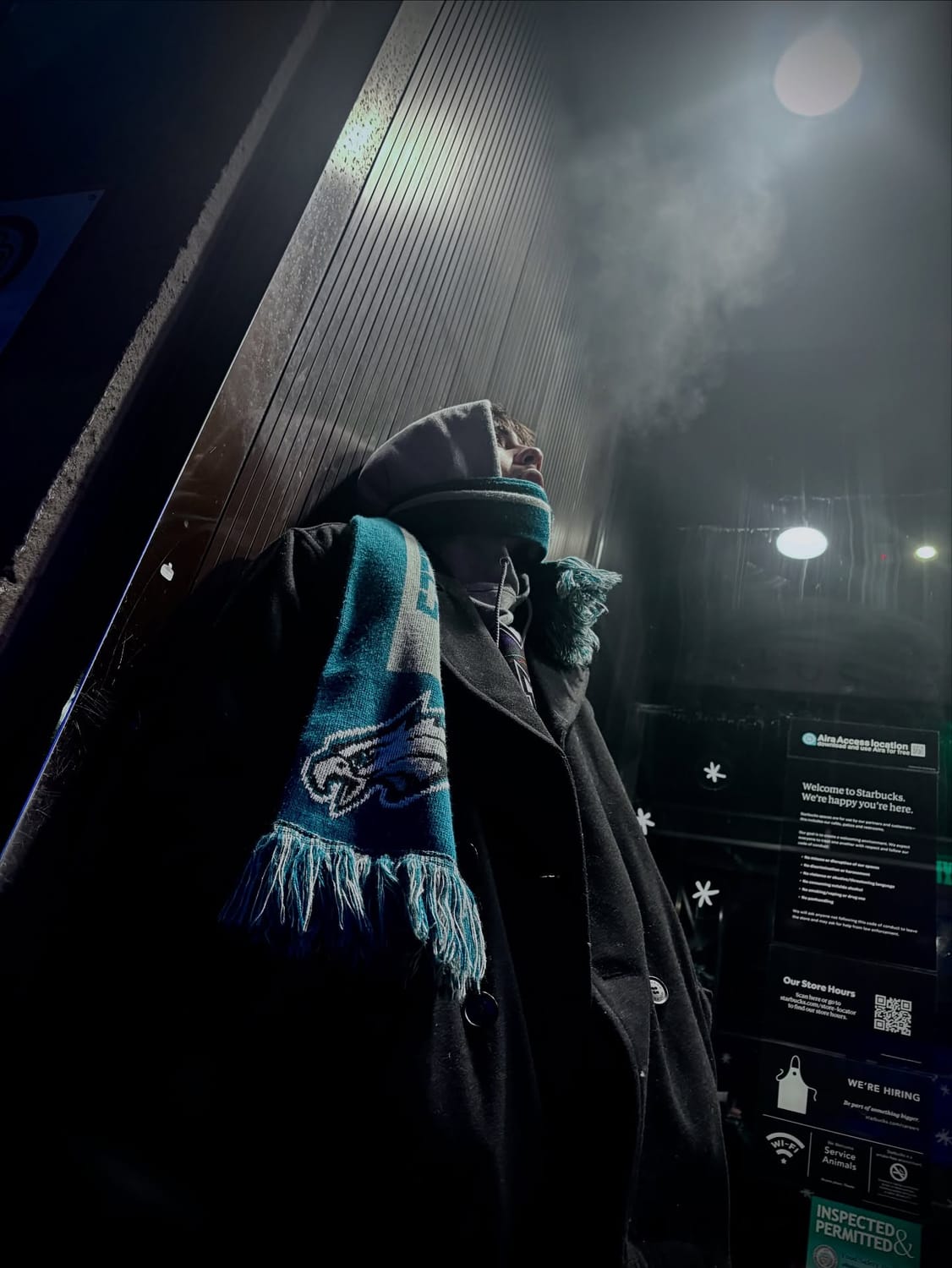 Night photograph of Eric's friend Krishna in a beanie and Philadelphia Eagles scarf, breath fogging in the cold